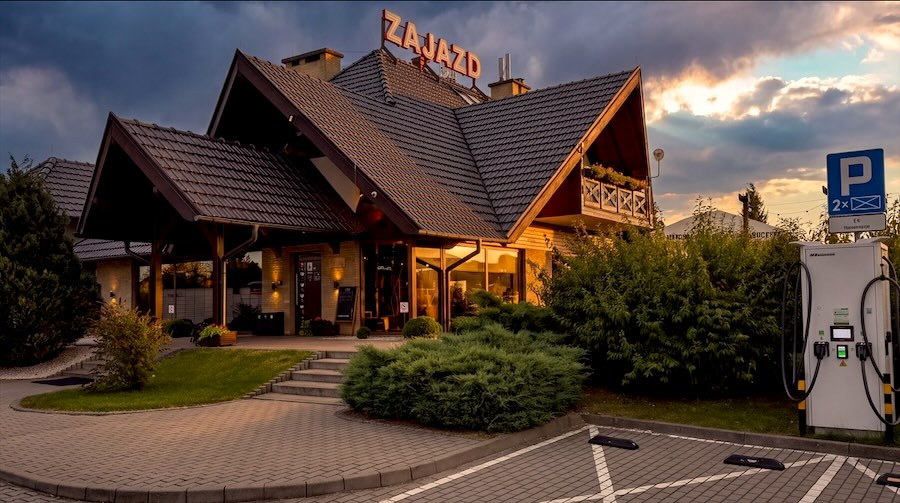 Wilczyniec o zachodzie słońca: wejście do zajazdu, parking i ładowarka samochodów elektrycznych