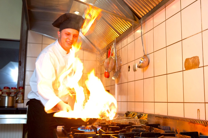 Szef kuchni Dominik Stępień flambiruje danie na patelni
