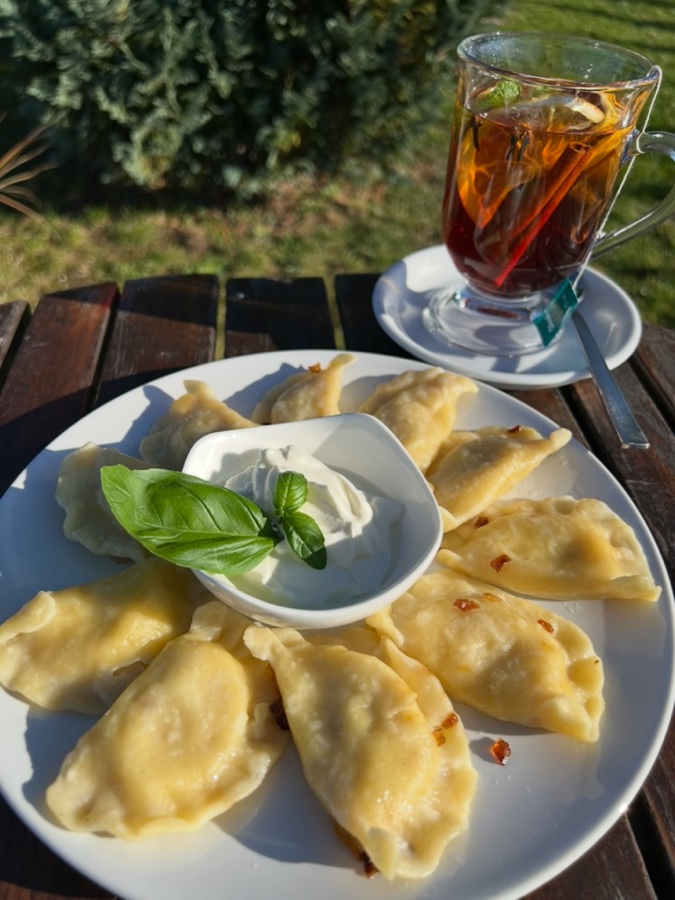 Ręcznie lepione pierogi ze śmietaną i herbata, podane na tarasie